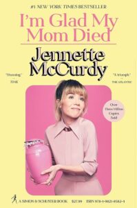 Book Cover for I'm Glad My Mom Died by Jennette McCurdy. It features the author holding a pink urn, wearing a pink dress, with a pink background.